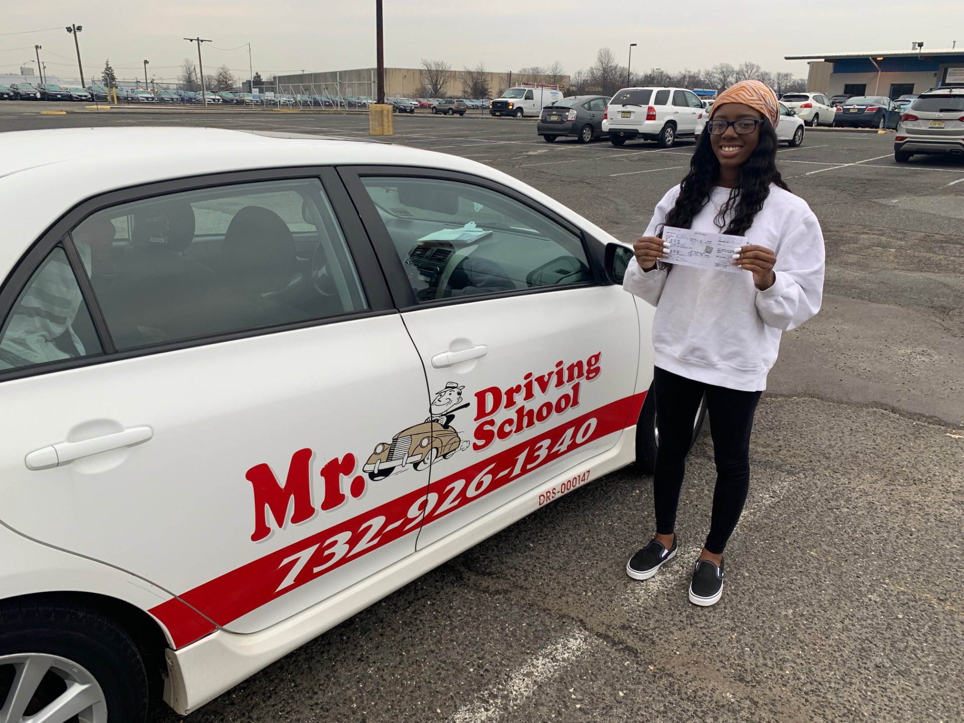 Student with license next to driving school car