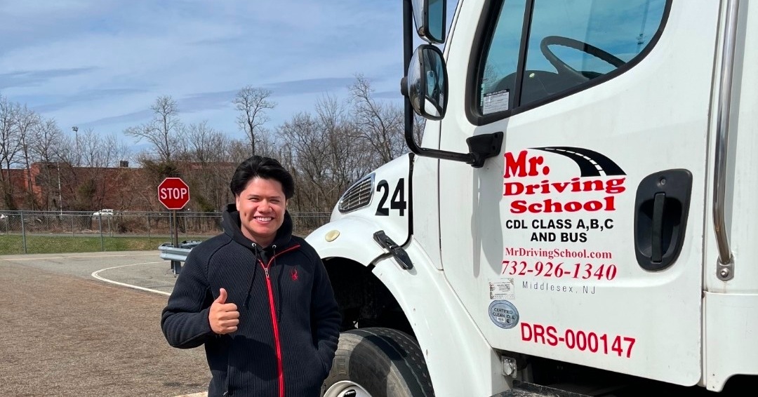 CDL graduate giving thumbs up by truck