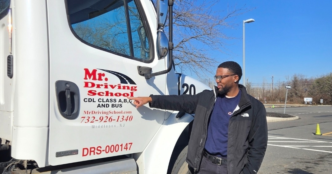 Graduate pointing to Mr. Driving School logo